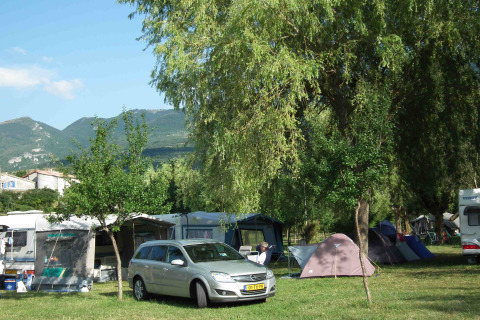 Camping Gorges de la Meouge con tiendas, caravanas y montañas verdes en Provence-Alpes-Côte d'Azur.