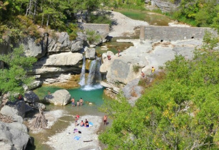 View of Gorges de la Méouge with people swimming by a waterfall near glamping in Provence-Alpes-Côte d’Azur.