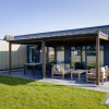 Modern glamping lodge at Friese Meren Villa’s, Friesland, with covered terrace and stylish outdoor furniture.