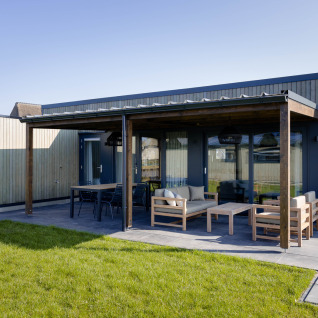 Moderno lodge glamping alle Friese Meren Villa’s in Frisia con terrazza coperta e arredi da esterno eleganti.