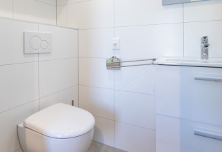 Modern bathroom with wall-mounted toilet and sink, bright decor at Friese Meren Villa’s - Luxe Lodges.