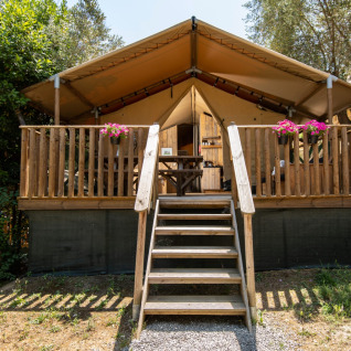 Alojamiento glamping en DivaCamp San Marino con tienda safari, terraza de madera y flores en el exterior.