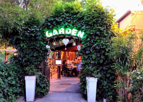 Ingang van DivaCamp San Marino - Safaritenten San Marino, omgeven door groen en een gezellige sfeer.