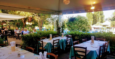 Buitenterras bij DivaCamp San Marino met gedekte tafels, omringd door groen en een ontspannen sfeer.