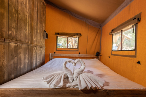 Interieur van glamping safaritent bij DivaCamp San Marino met tweepersoonsbed en handdoekzwanen decoratie.
