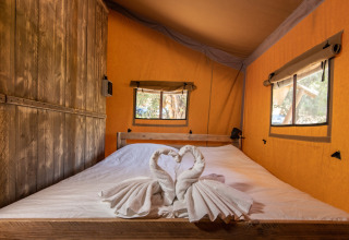 Interieur van glamping safaritent bij DivaCamp San Marino met tweepersoonsbed en handdoekzwanen decoratie.