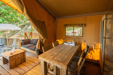 Glamping accommodatie DivaCamp San Marino met rustieke houten tafel en knus terras in safaritent.
