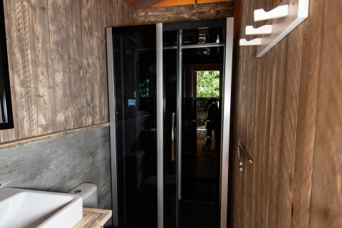 Moderne badkamer met houten wanden en glazen douche bij DivaCamp San Marino - Safaritenten San Marino.