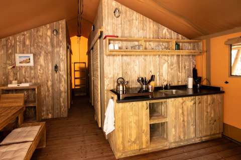 Binnenaanzicht van een DivaCamp San Marino safaritent met houten keuken en eethoek.