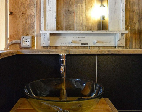 Rustieke badkamer met glazen wastafel, houten wanden, spiegel en sfeerverlichting bij DivaCamp San Marino.