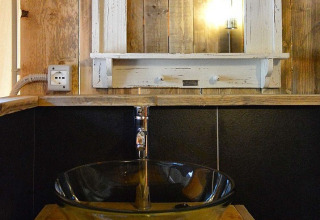 Rustieke badkamer met glazen wastafel, houten wanden, spiegel en sfeerverlichting bij DivaCamp San Marino.