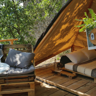Hébergement glamping 'Novanta - Boomhut Toscane' avec terrasse extérieure et lit confortable sous tente.