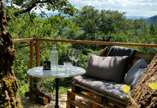 Terrazza accogliente con divano in pallet e tavolino presso Novanta - Boomhut Toscane glamping, tra gli alberi.