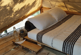 Vista interna della glamping Novanta in Toscana, letto confortevole e atmosfera accogliente.