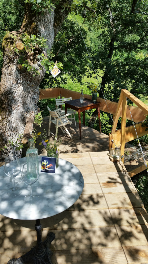 Treehouse glamping med borde og stole i skyggen blandt træer, Novanta - Boomhut Toscane, Italien.