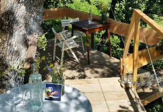 Glamping in una casa sull'albero con tavoli e sedie tra gli alberi, Novanta - Boomhut Toscane, Italia.