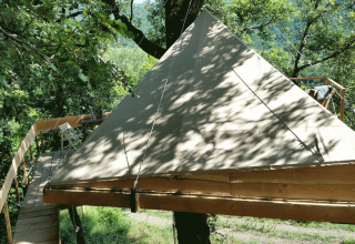 Hébergement glamping 'Novanta - Boomhut Toscane' avec tente et terrasse dans une cabane perchée en forêt.