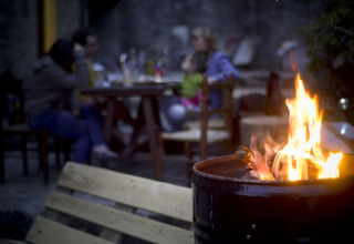 Glamping at Novanta - Boomhut Toscane with a campfire in front and guests relaxing at a table in the background.