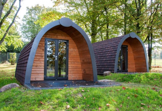 Dos cabañas glamping de madera en Campingpark am Gederner See en Hessen, rodeadas de árboles y naturaleza.