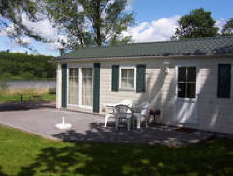 Terrasse bei Campingpark am Gederner See - Glamping Hessen mit weißen Gartenmöbeln vor Ferienhaus.