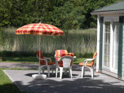 Sitzbereich im Freien mit bunten Stühlen und Sonnenschirm bei Campingpark am Gederner See - Glamping Hessen.