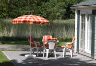 Udendørs siddeområde med farverige stole og parasol ved Campingpark am Gederner See - Glamping Hessen.