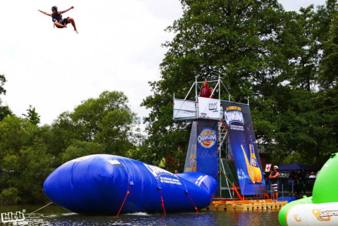Une personne s'envole d'un coussin gonflable géant au Campingpark am Gederner See - Glamping Hessen, en plein air.
