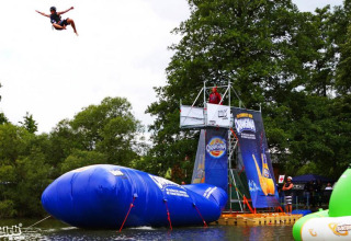 Persoon vliegt door de lucht vanaf een groot opblaasobject bij Campingpark am Gederner See - Glamping Hessen.