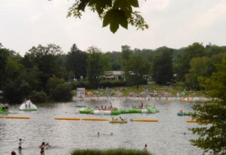 View of the lake at Campingpark am Gederner See - Glamping Hessen with swimming guests and lush green scenery.