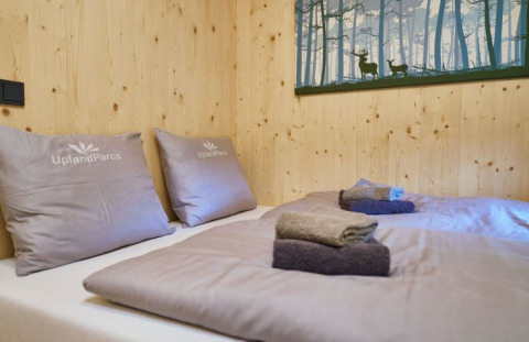 Camera accogliente presso UplandParcs Sauerland - Boomhutten con pareti in legno, letti e asciugamani piegati.