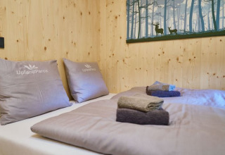 Soveværelse i UplandParcs Sauerland - Boomhutten, hyggelige senge og håndklæder i træindrettet glamping.