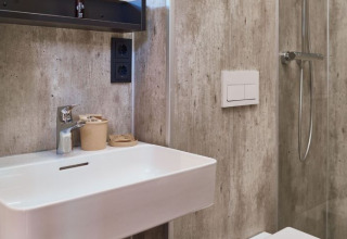 Moderne badkamer met wastafel, kraan en douche in glampingaccommodatie UplandParcs Sauerland, Duitsland.