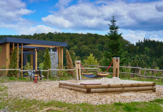 Alojamiento glamping UplandParcs Sauerland - Boomhutten Noordrijn-Westfalen con área de juegos y vista al bosque.