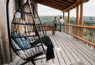 Person entspannt auf einer Hängeschaukel auf einer Holzterrasse, zwei genießen die Aussicht bei UplandParcs Sauerland.