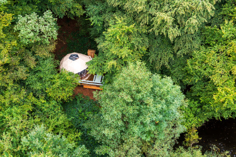 Glamping Auvergne – Glampingtent verscholen in het groene bos van Auvergne-Rhône-Alpes, vanuit de lucht gezien.