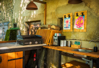 Cocina exterior en Glamping Auvergne – Glampingtenten Auvergne-Rhone-Alpes con parrilla, fregadero y cafetera.