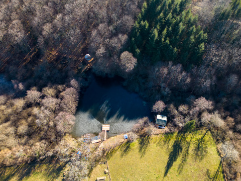 Luftaufnahme von Glamping Auvergne an einem Waldteich, umgeben von Bäumen in Auvergne-Rhône-Alpes.