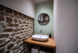 Bagno glamping moderno con muro in pietra, piano in legno, lavandino rotondo e specchio in Alvernia.