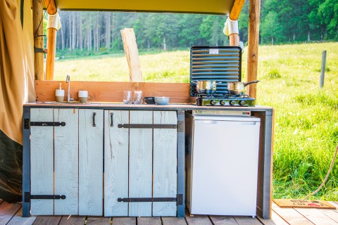 Cucina all'aperto con lavello, fornello e frigorifero a Glamping Auvergne, regione Auvergne-Rhone-Alpes.