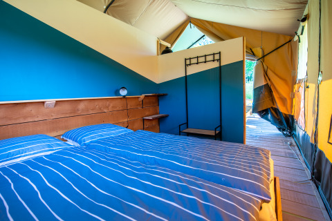 Cozy glamping tent in Auvergne-Rhone-Alpes featuring a double bed, wood flooring, and stylish decor.