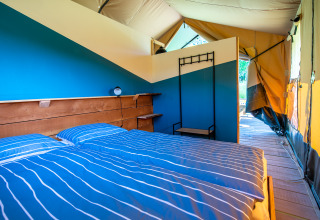Cozy glamping tent in Auvergne-Rhone-Alpes featuring a double bed, wood flooring, and stylish decor.