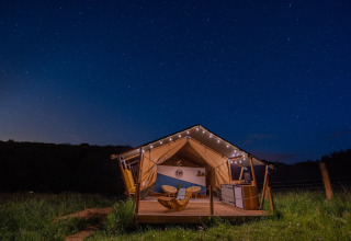Tenda glamping in Auvergne-Rhône-Alpes di notte, illuminata sotto un cielo stellato in un ambiente sereno.