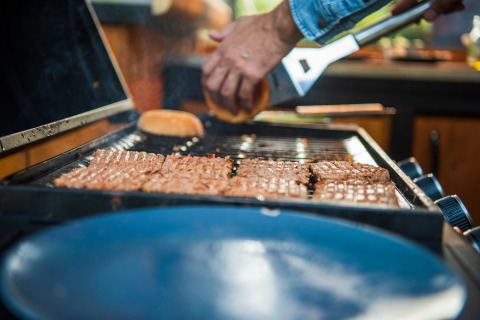 Una persona griglia hamburger e panini al Glamping Auvergne – Glampingtenten Auvergne-Rhone-Alpes.