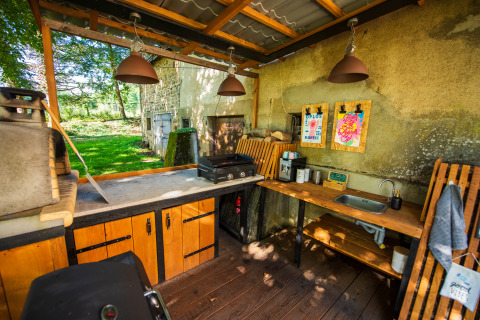 Cuisine extérieure avec grill, évier et meubles en bois au Glamping Auvergne dans la région Rhône-Alpes.