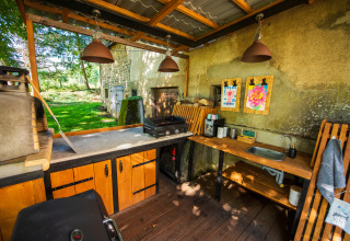 Udendørs køkkenområde med grill, vask og træmøbler på Glamping Auvergne i det naturskønne Rhone-Alpes.