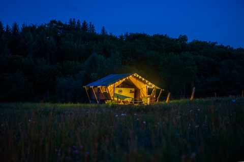 Verlicht glamping tent in de natuur in de avond, Glamping Auvergne – Glampingtenten Auvergne-Rhone-Alpes.