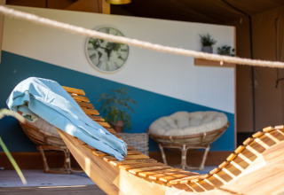 Interior acogedor de glamping con tumbona de madera, toalla azul y sillones en Auvergne-Rhone-Alpes.