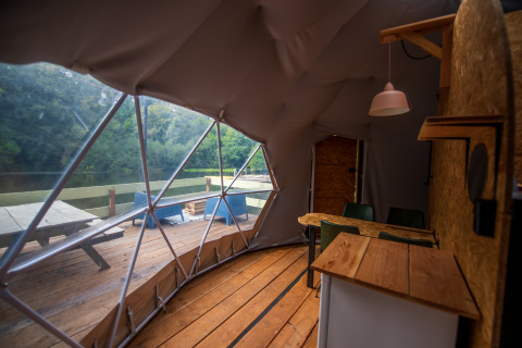 Innenansicht eines Glampingzeltes in Auvergne-Rhône-Alpes mit Blick auf Terrasse und See.