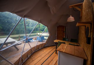 Interno di una tenda glamping in Alvernia-Rodano-Alpi con vista sulla terrazza e il lago fuori.