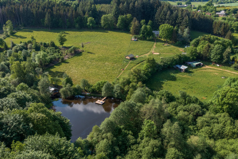 Luftfoto af Glamping Auvergne med telte ved en dam og grønne marker i Auvergne-Rhône-Alpes, Frankrig.